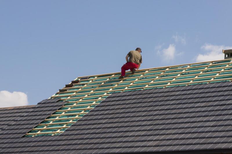 man putting roof tiles